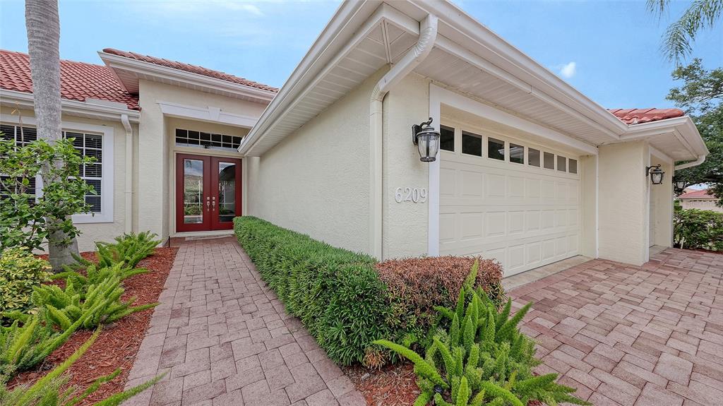 A single-story house with a red tile roof, three-car garage, and a landscaped front yard — 6209 CYPRESS BEND COURT, BRADENTON, FL