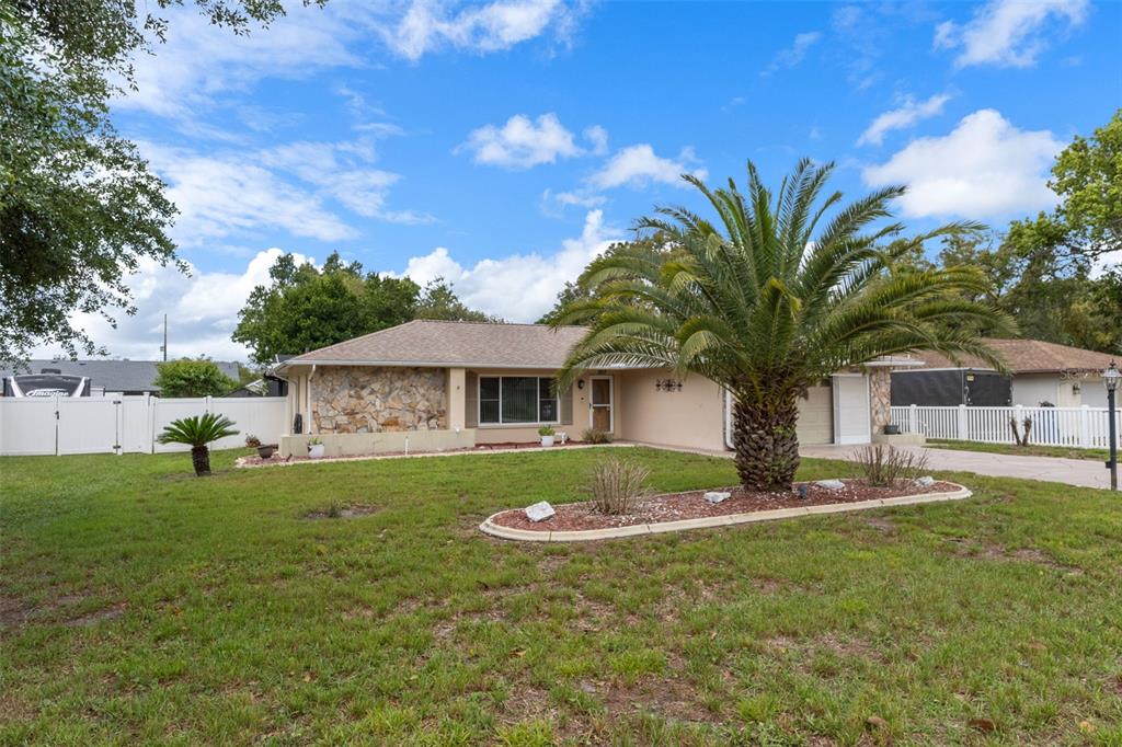 A single-story house with a stone facade, a palm tree, and a white fence — 3217 ABELINE ROAD, SPRING HILL, FL