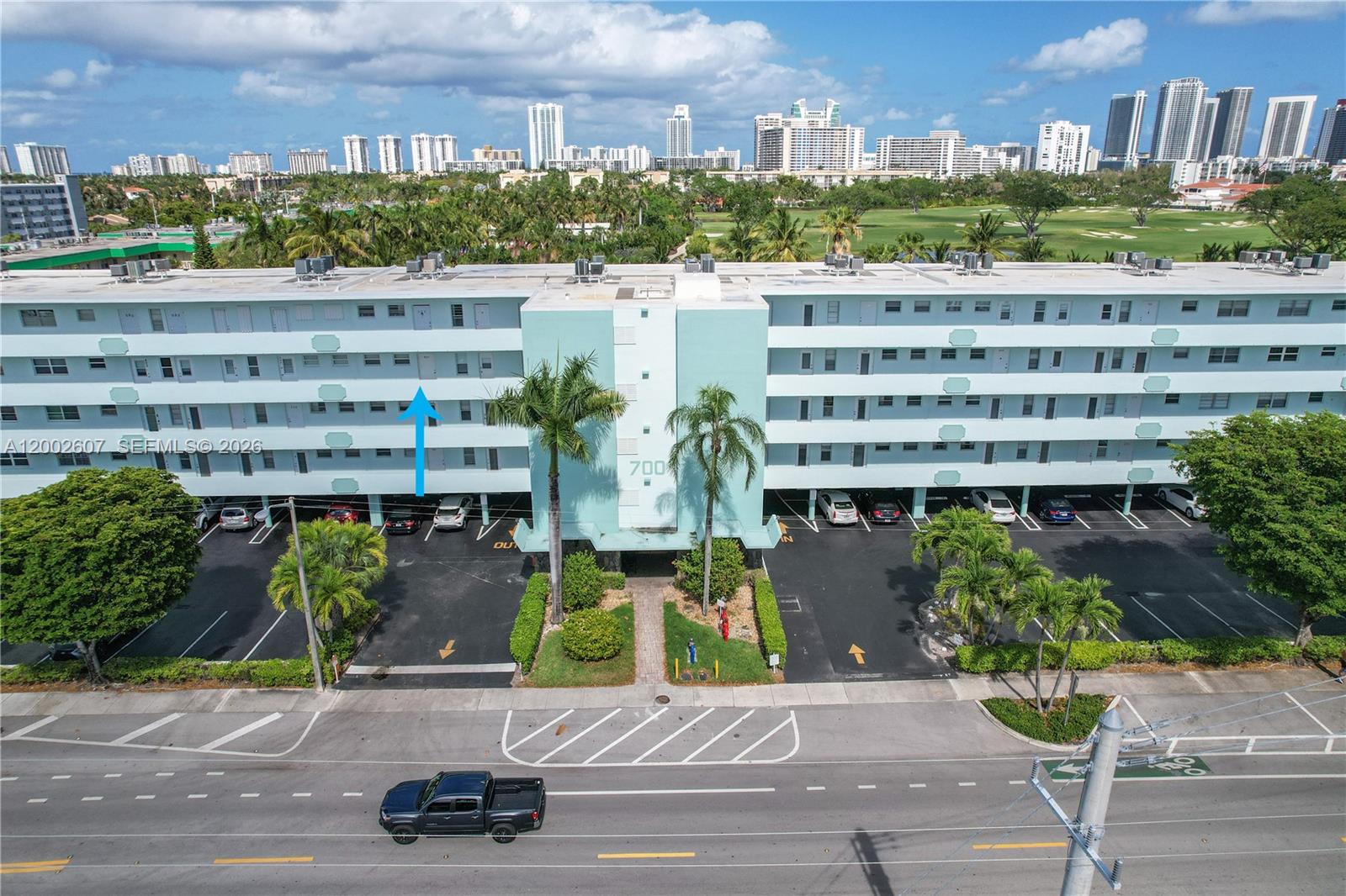 An aerial view shows the exterior of a multi-story apartment building with a parking lot — 700 NE 14th Ave # 407, Hallandale Beach FL 33009, HALLANDALE BEACH, FL