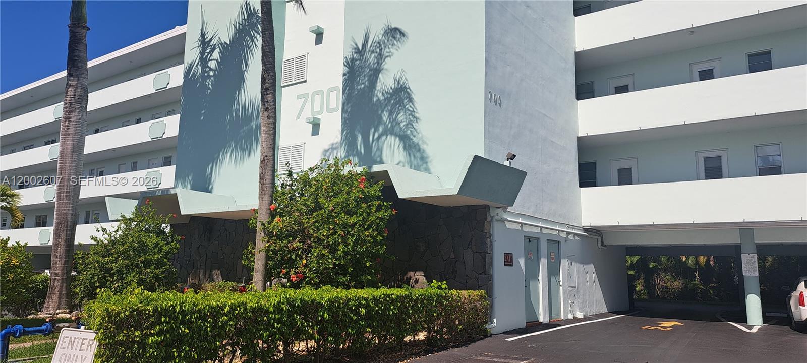 The exterior of a multi-story apartment building features a light blue facade and stone accents — 700 NE 14th Ave # 407, Hallandale Beach FL 33009, HALLANDALE BEACH, FL