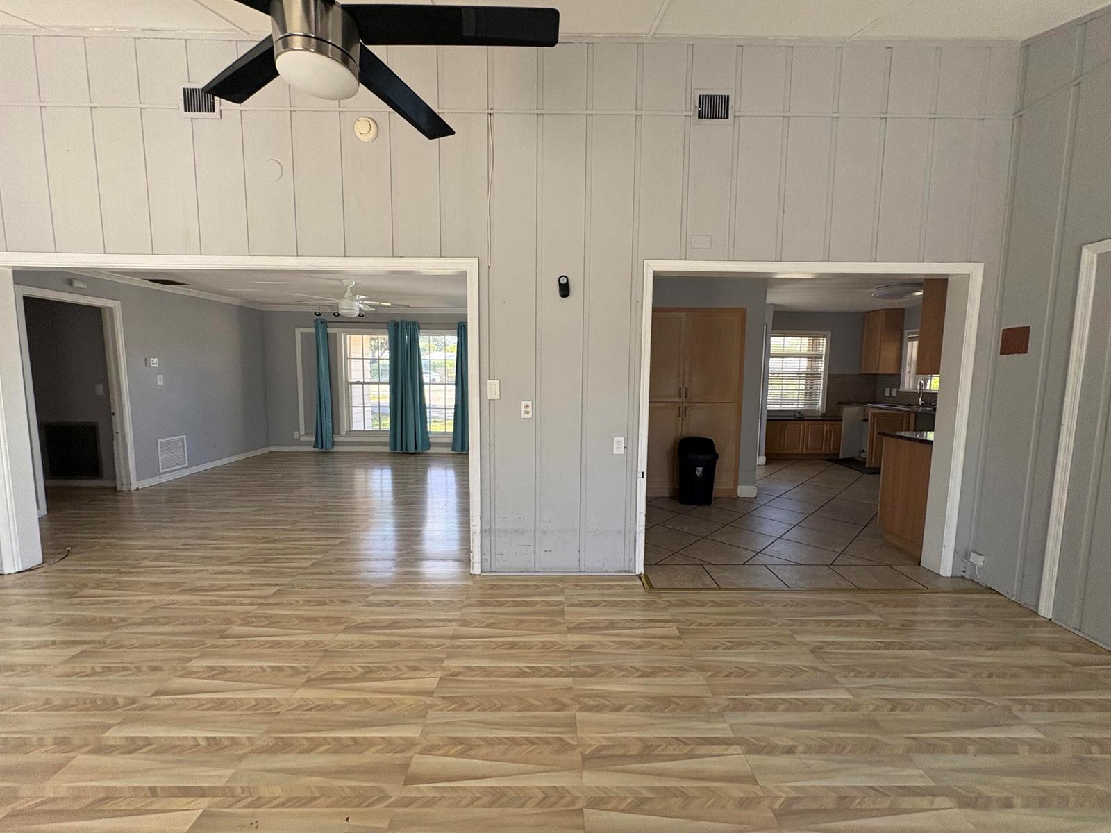 A view of a living area with wood-look flooring, two doorways, and a ceiling fan — 202 Palm Court, Delray Beach FL 33444, DELRAY BEACH, FL