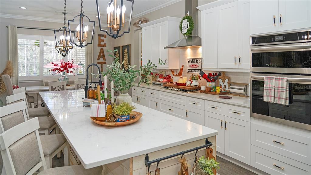 A bright kitchen features white cabinetry, a large quartz island, and stainless steel double ovens — 4801 MAJESTIC HILLS LOOP, BROOKSVILLE, FL