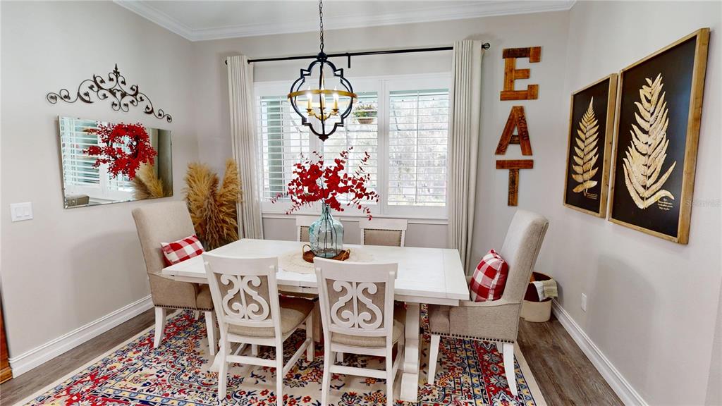 A dining room features a white table, four chairs, a chandelier, and wall decor — 4801 MAJESTIC HILLS LOOP, BROOKSVILLE, FL