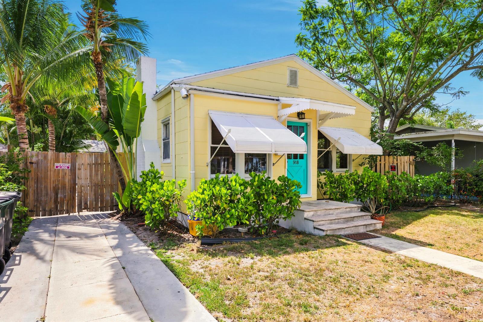 A yellow cottage with a turquoise door, white awnings, and a concrete driveway — 918 N K Street, FL 33460, FL