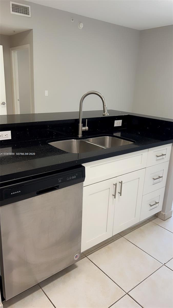 A kitchen features a stainless steel dishwasher, white cabinets, and a black countertop — 7350 NW 114th Ave # 103, Doral FL 33178, DORAL, FL