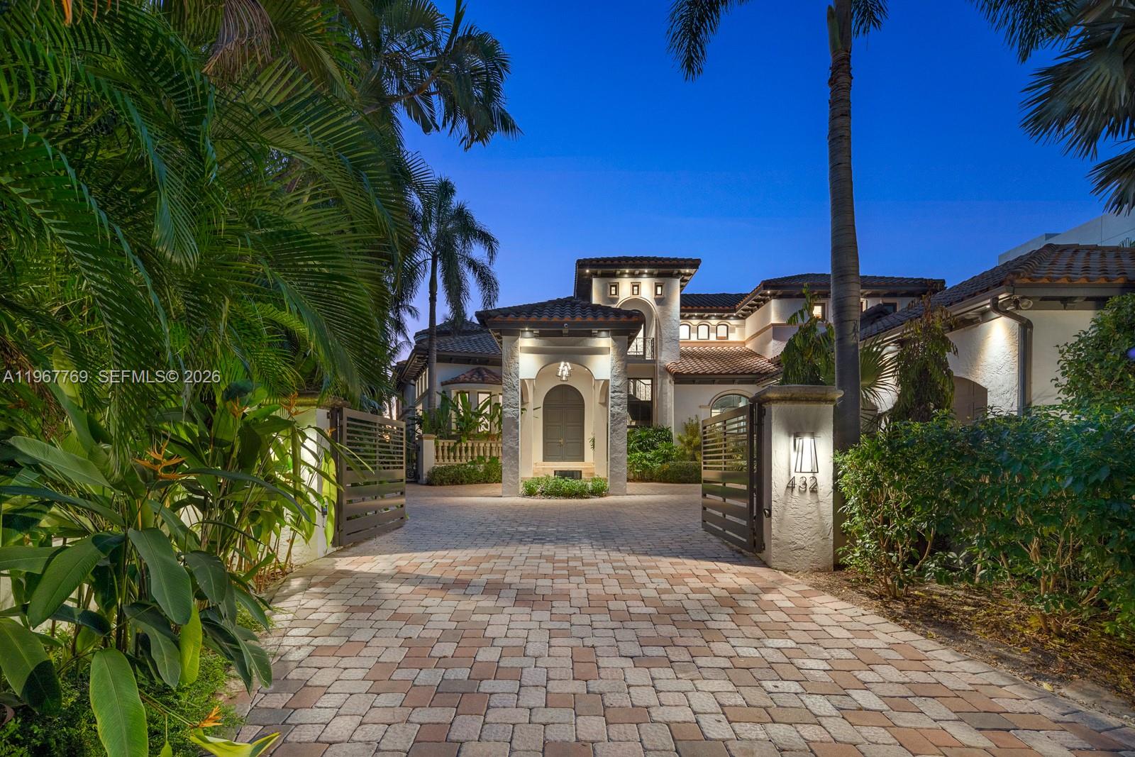 A gated paver driveway leads to the entrance of a multi-story Mediterranean-style home at dusk — 432 S Hibiscus Dr, Miami Beach FL 33139, MIAMI BEACH, FL