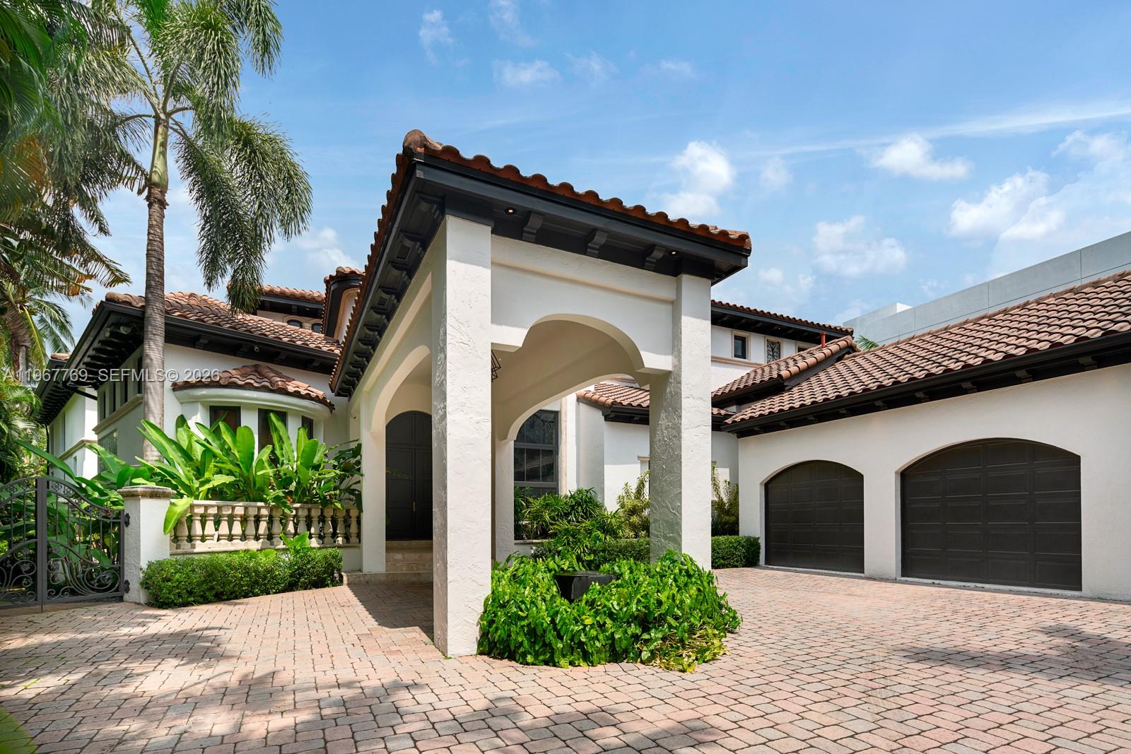 The exterior of a Mediterranean-style home features a covered entryway, a brick driveway, and two garages — 432 S Hibiscus Dr, Miami Beach FL 33139, MIAMI BEACH, FL