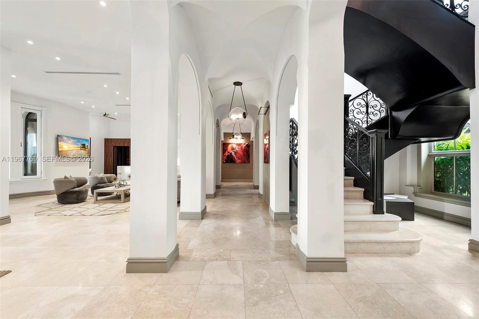 A bright hallway with arched columns leads to a staircase with a black railing — 432 S Hibiscus Dr, Miami Beach FL 33139, MIAMI BEACH, FL