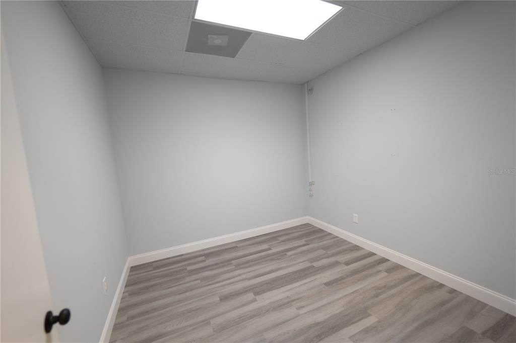 An empty office room features light gray walls, white trim, and wood-look laminate flooring — 1209 TECH BOULEVARD UNIT 211, TAMPA, FL