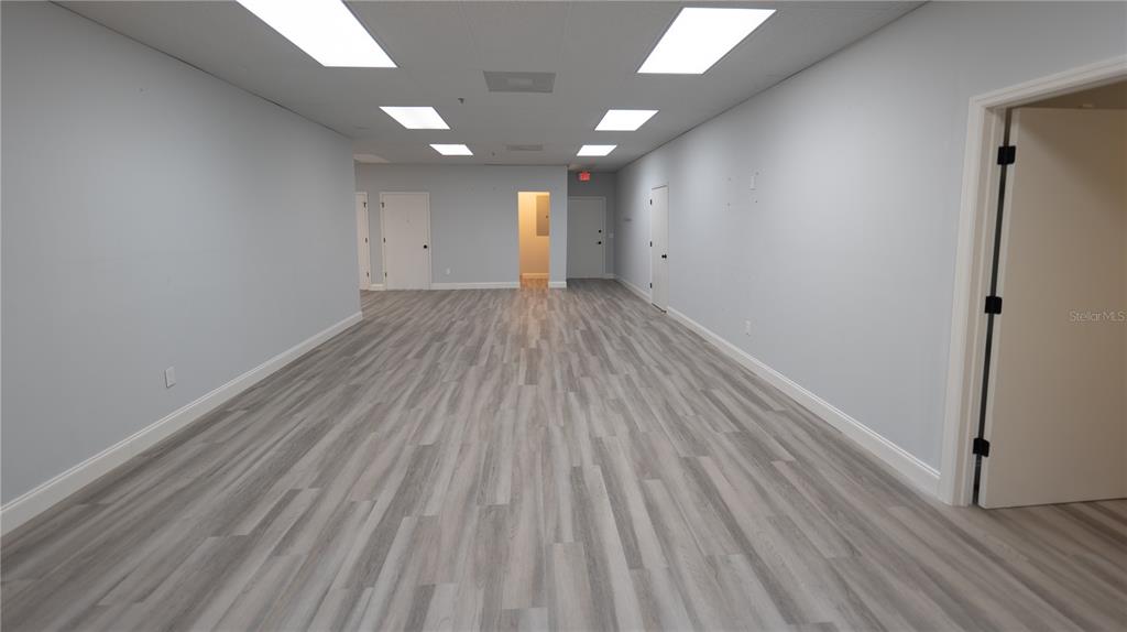 An empty office space features light gray walls, wood-look vinyl flooring, and recessed ceiling lights — 1209 TECH BOULEVARD UNIT 211, TAMPA, FL