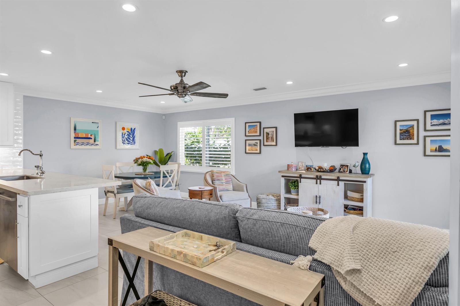 A living room with a striped sofa, dining area, and television mounted above a cabinet — 234 Seabreeze Circle, Jupiter FL 33477, JUPITER, FL