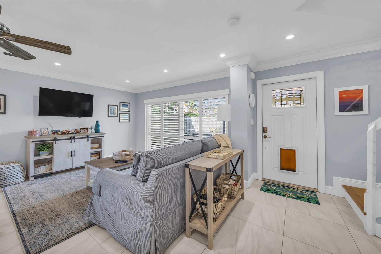 A living room features a gray sofa, a media console, and a white front door — 234 Seabreeze Circle, Jupiter FL 33477, JUPITER, FL