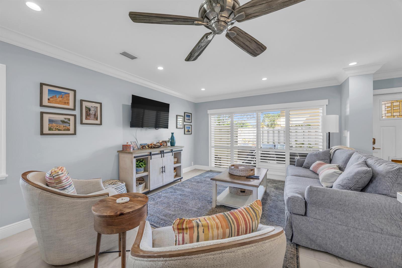 A living room features a grey sofa, two armchairs, a television, and a ceiling fan — 234 Seabreeze Circle, Jupiter FL 33477, JUPITER, FL