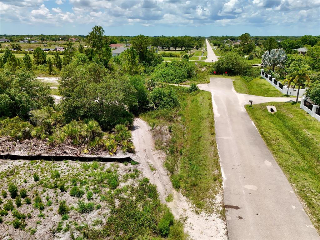 An aerial view shows a paved road ending at a vacant, wooded lot — 0 60TH AVENUE NORTHEAST AVENUE NE, NAPLES, FL