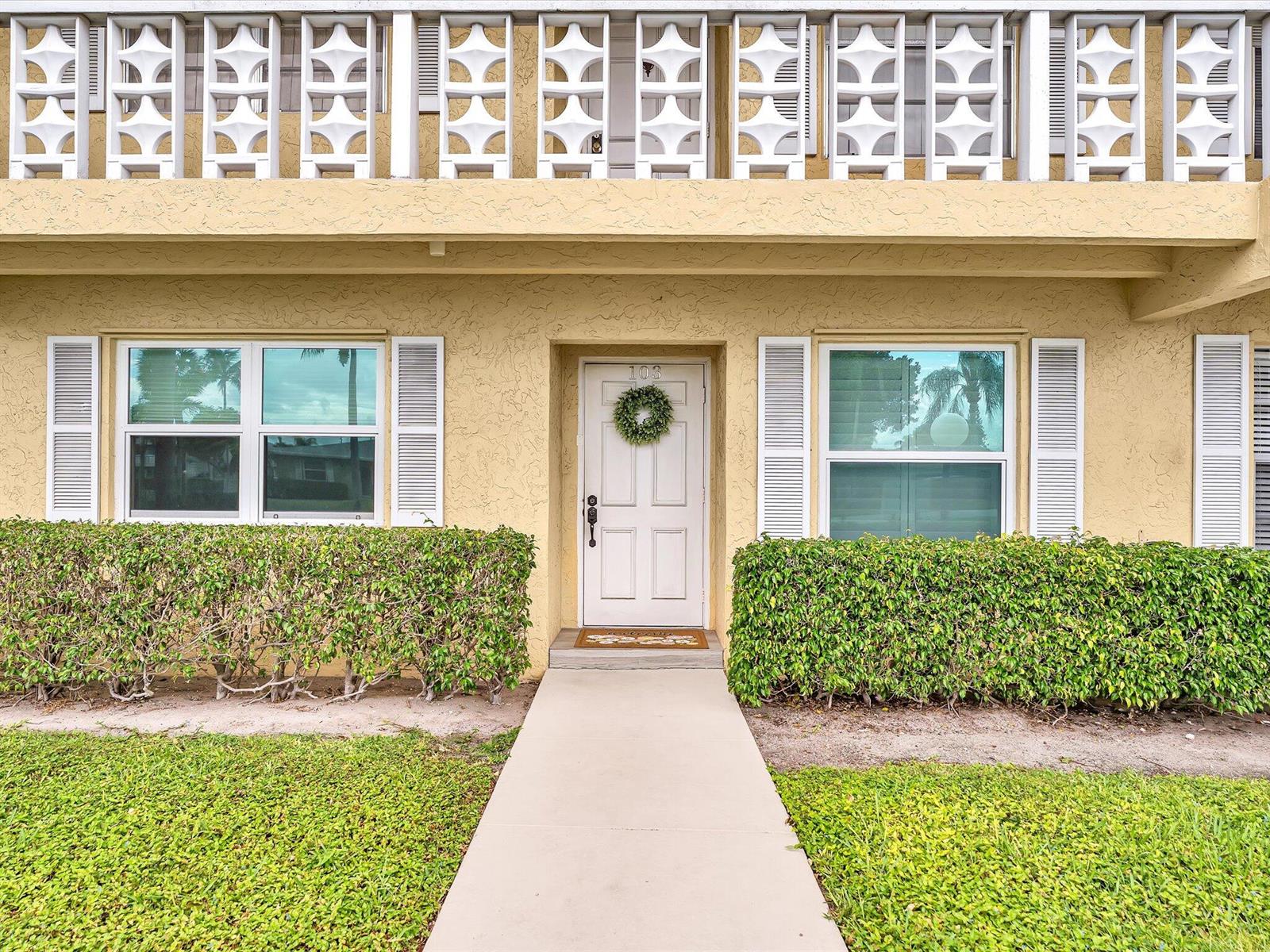 A yellow exterior building features a white front door with a wreath and hedges — 1151 Calamondin Terrace, Delray Beach FL 33445, DELRAY BEACH, FL