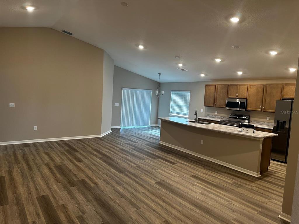 An open-concept living area features wood-look flooring, a kitchen island, and recessed lighting — 1391 MOUNTAIN FLOWER LANE, DAVENPORT, FL