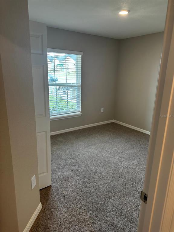 A small, empty bedroom with gray walls, carpeted flooring, and a window with blinds — 1391 MOUNTAIN FLOWER LANE, DAVENPORT, FL