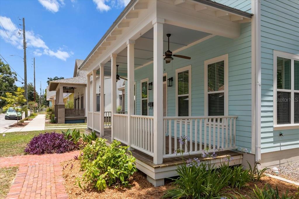 A light blue house features a covered front porch with white railings and ceiling fans — 619 NW 3RD STREET, GAINESVILLE, FL