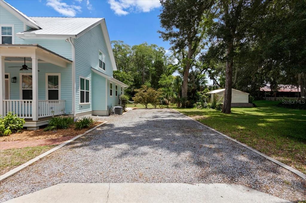 A light blue house with a gravel driveway and a small shed in the backyard — 619 NW 3RD STREET, GAINESVILLE, FL