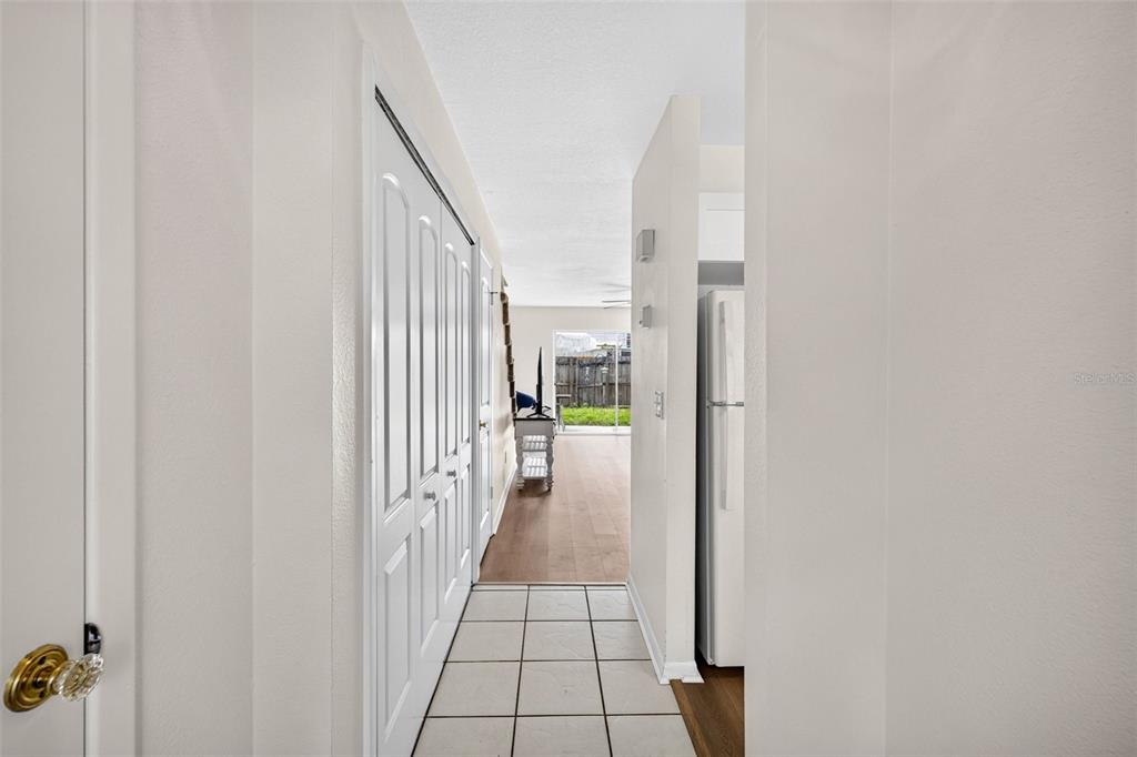 A hallway with white tile flooring leads to a living area with wood-look floors — 1760 MILL RUN CIRCLE, TAMPA, FL