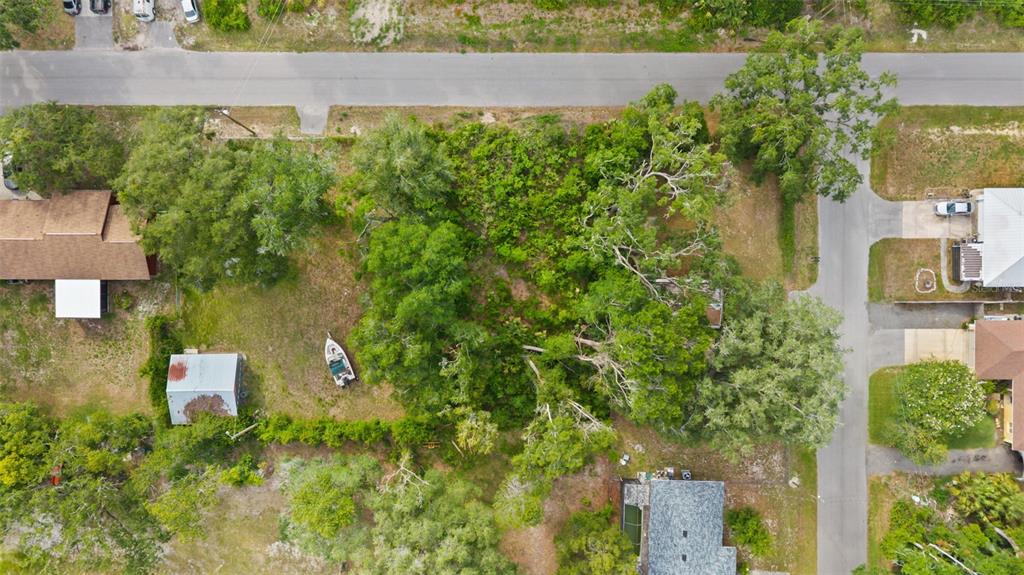 An aerial view shows a wooded residential lot with a small boat and shed — 15177 SPOKANE ROAD, SPRING HILL, FL