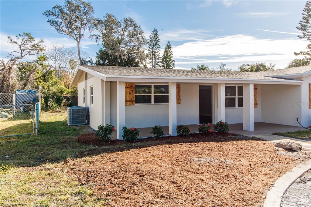 A single-story house with a covered porch, wood shutters, and a mulched front yard — 7122 ASTOR DRIVE, NEW PORT RICHEY, FL