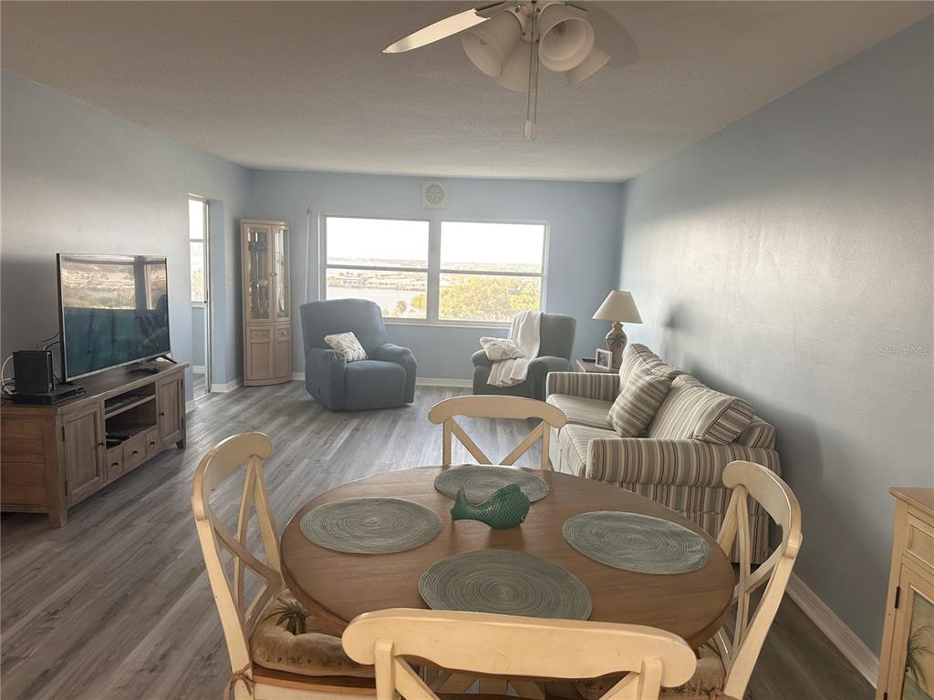 A living and dining area features light blue walls, wood-look flooring, and a view of water — 4725 COVE CIRCLE UNIT 804, ST PETERSBURG, FL