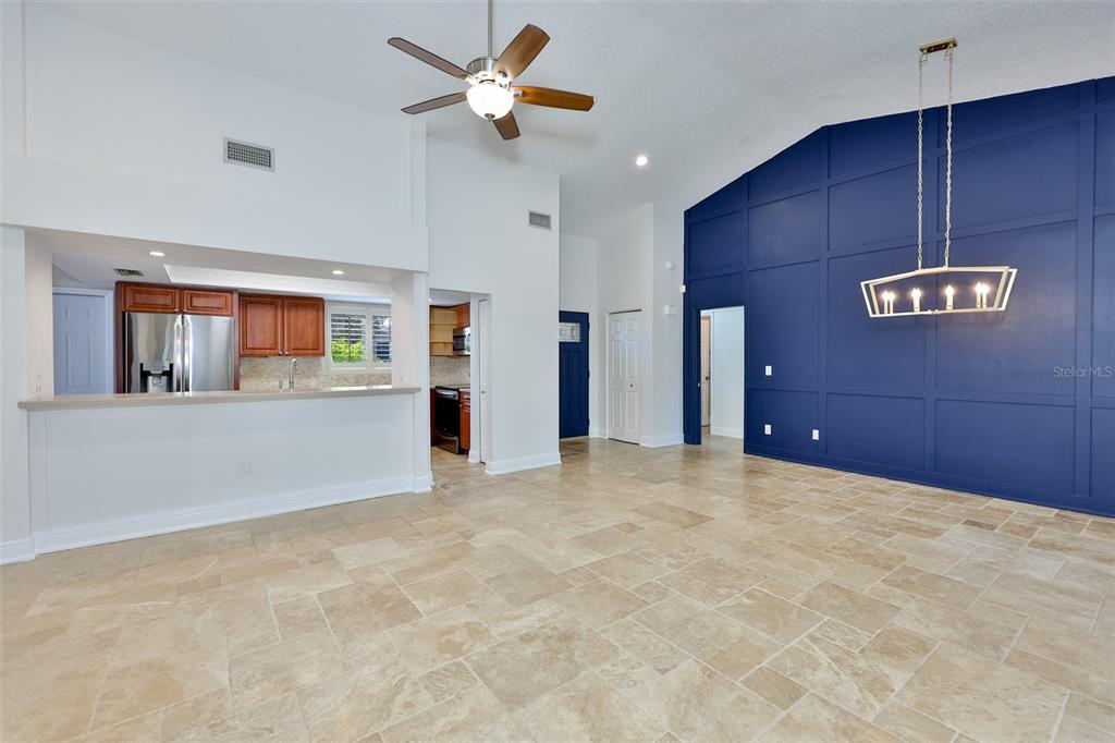 A spacious room features light tile flooring, a blue accent wall, and a kitchen pass-through — 14651 VILLAGE GLEN CIRCLE, TAMPA, FL