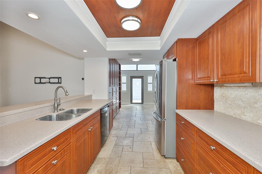 A galley kitchen features wood cabinets, stone countertops, tile flooring, and a wood-paneled ceiling — 14651 VILLAGE GLEN CIRCLE, TAMPA, FL