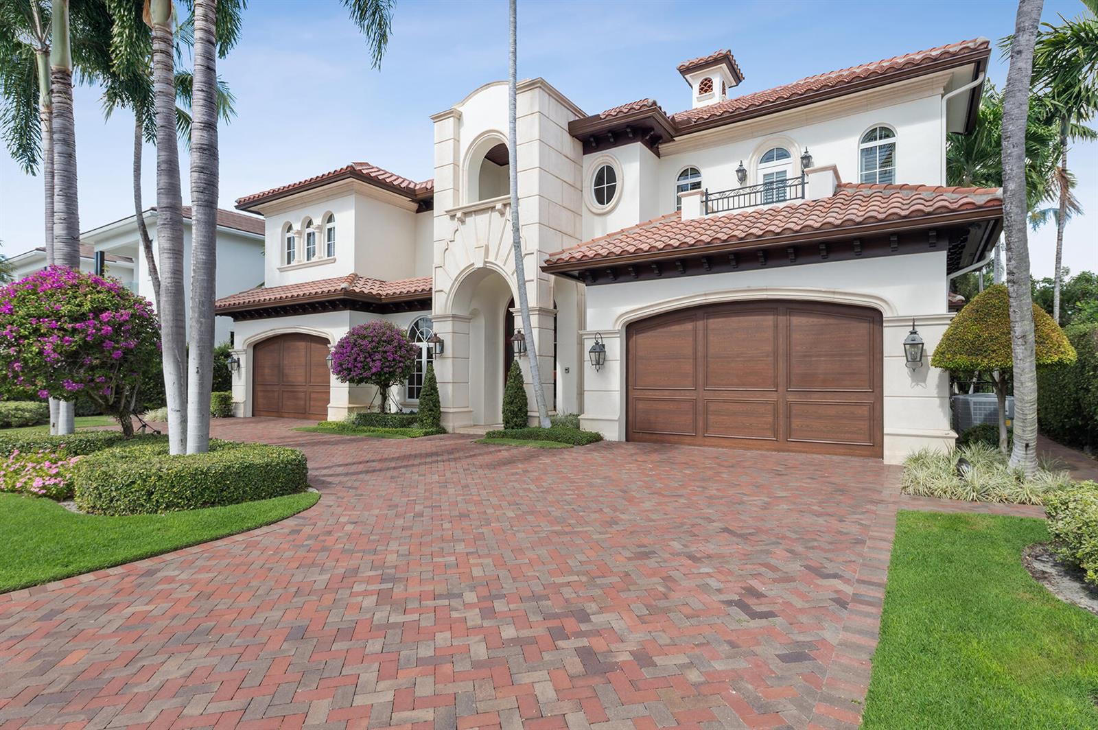 A two-story Mediterranean-style house features a brick driveway, arched garage doors, and palm trees — 293 Sabal Palm Terrace, Boca Raton FL 33432, BOCA RATON, FL
