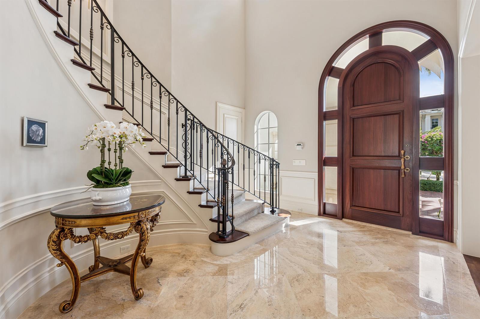 A grand foyer features a curved staircase with iron railings, marble floors, and arched doors — 293 Sabal Palm Terrace, Boca Raton FL 33432, BOCA RATON, FL