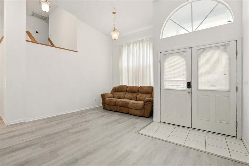 A living room with high ceilings, light wood flooring, and a brown sofa — 10402 ASHLEY OAKS DRIVE, RIVERVIEW, FL