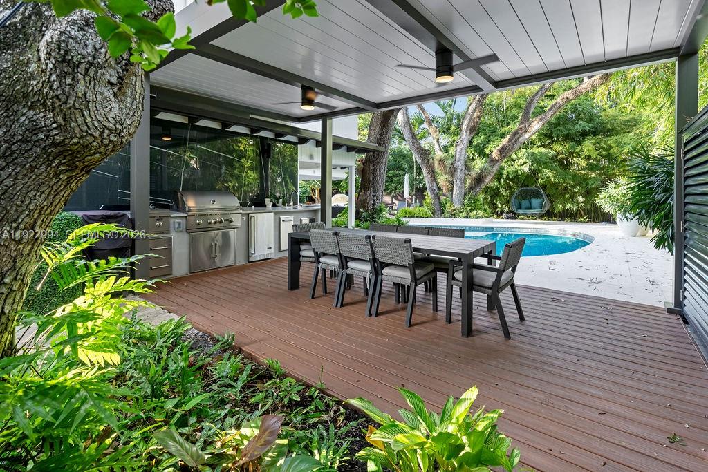 A covered outdoor patio features a dining set, a built-in grill, and a swimming pool — 4095 Battersea Rd, Miami FL 33133, MIAMI, FL