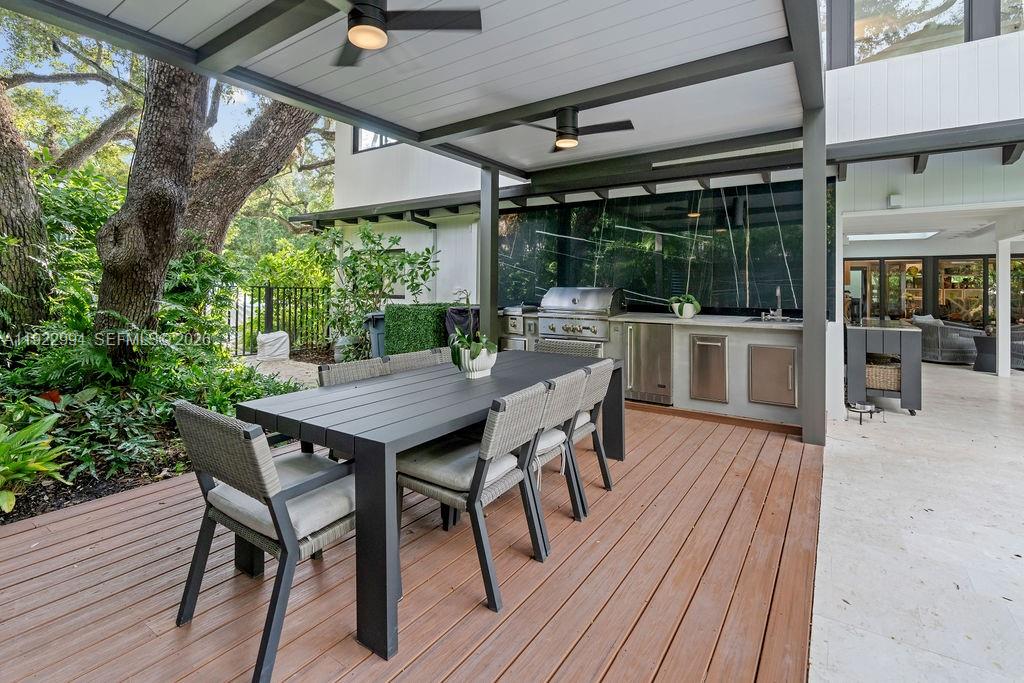 An outdoor patio features a dining table, a built-in grill station, and a wooden deck — 4095 Battersea Rd, Miami FL 33133, MIAMI, FL