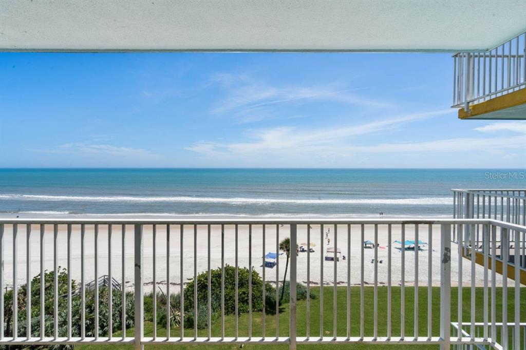 A balcony view overlooking a sandy beach, ocean waves, and a clear blue sky — 5201 S ATLANTIC AVENUE UNIT 703A, NEW SMYRNA BEACH, FL