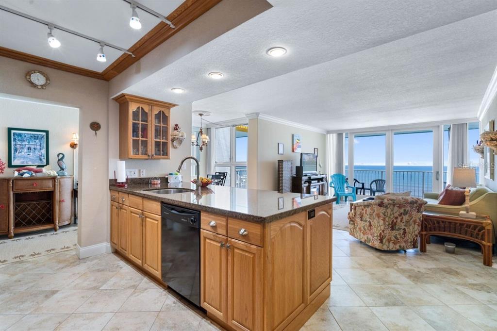 A kitchen with wood cabinets and granite countertops opens into a living area with ocean views — 5201 S ATLANTIC AVENUE UNIT 703A, NEW SMYRNA BEACH, FL