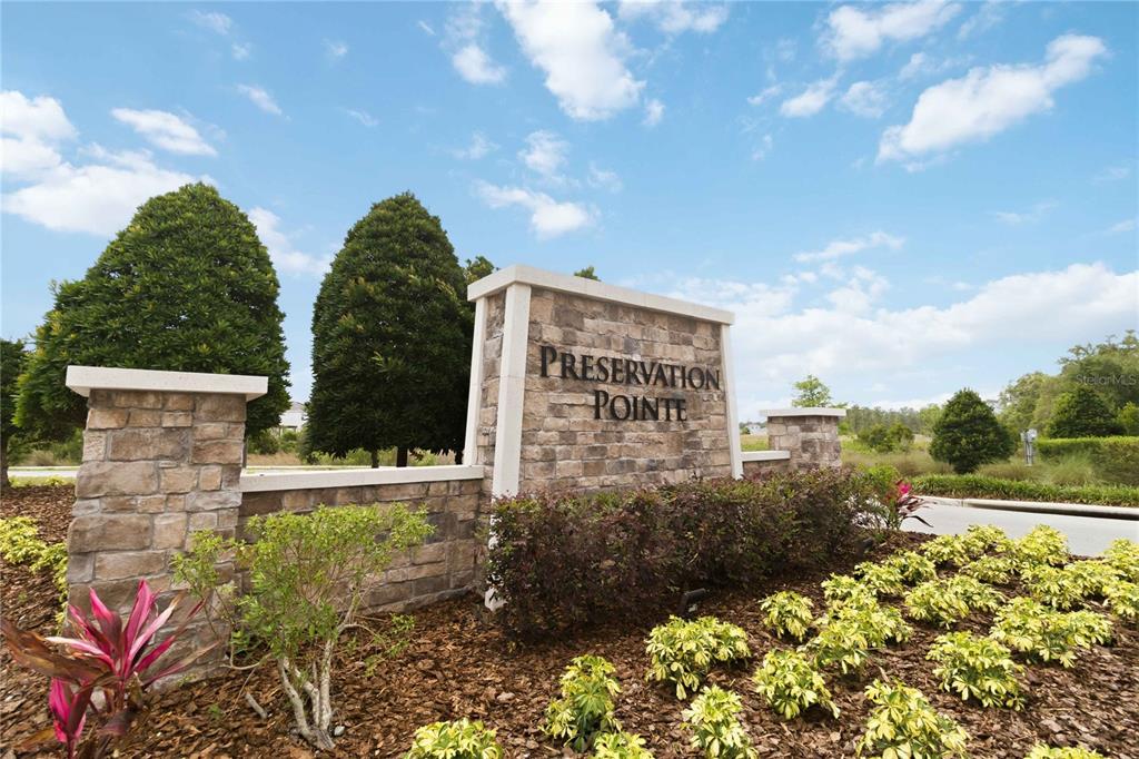 A stone monument sign for Preservation Pointe stands in a landscaped garden under a blue sky — 1275 ISLAND SLOUGH LANE, DAVENPORT, FL