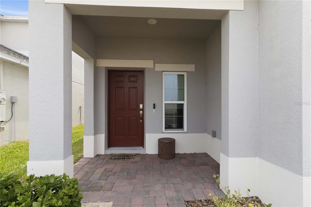 A covered entryway features a brown front door, a paver floor, and a small window — 1275 ISLAND SLOUGH LANE, DAVENPORT, FL