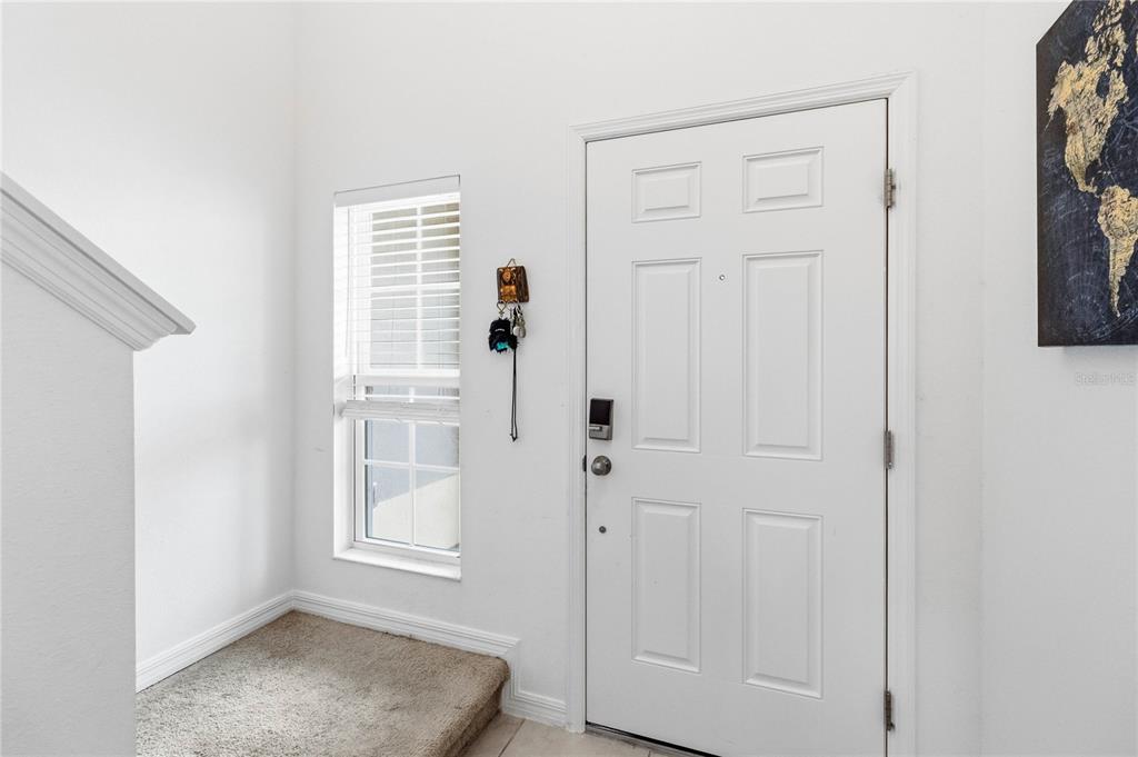 A white front door and a window with blinds are located in a carpeted entryway — 1275 ISLAND SLOUGH LANE, DAVENPORT, FL