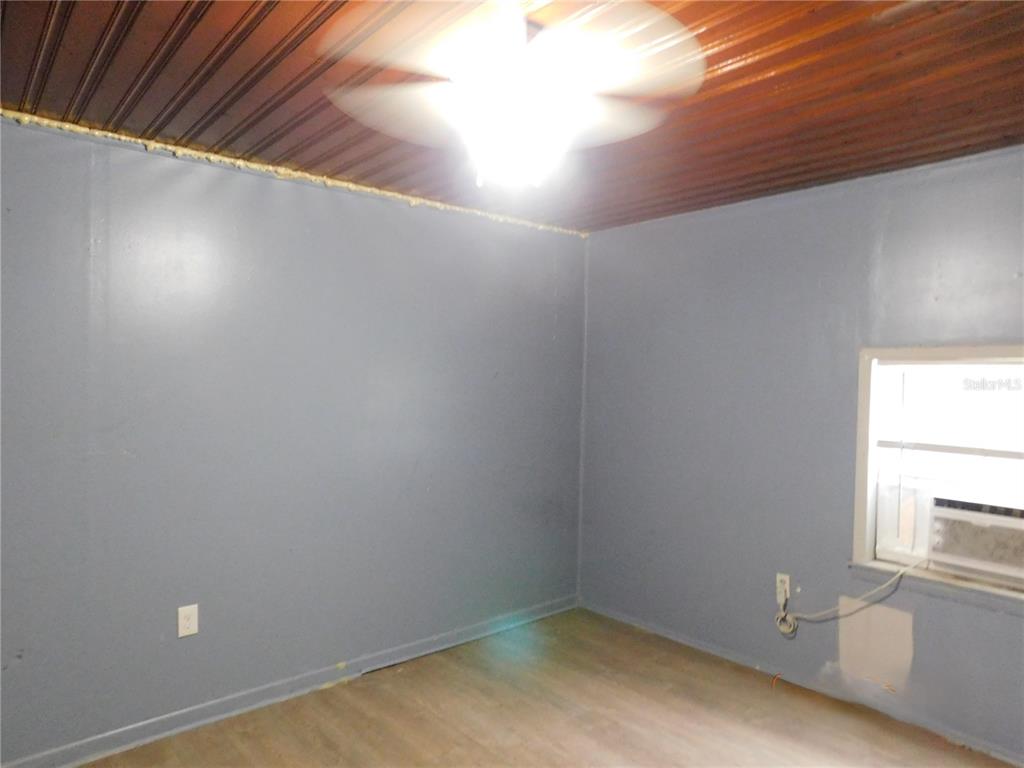 A bedroom with gray walls, wood-look flooring, a ceiling fan, and a window air conditioner — 1402 MALUHIA DRIVE, TAMPA, FL