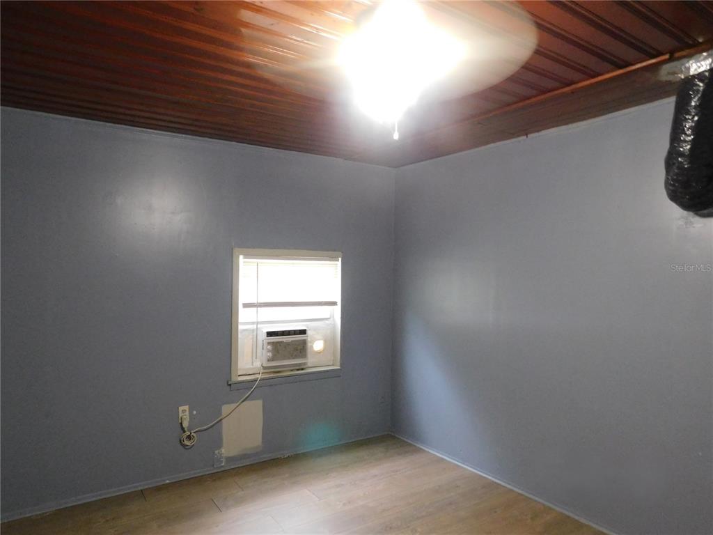 A bedroom with gray walls, wood-look flooring, and a window air conditioning unit — 1402 MALUHIA DRIVE, TAMPA, FL