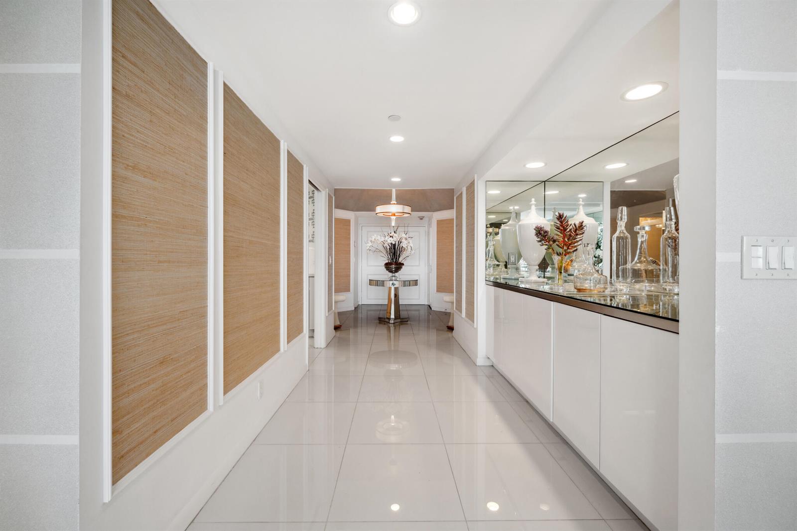 A bright hallway features white tile floors, wood-paneled walls, and a mirrored console area — 2100 S Ocean Boulevard # 607n, Palm Beach FL 33480, PALM BEACH, FL