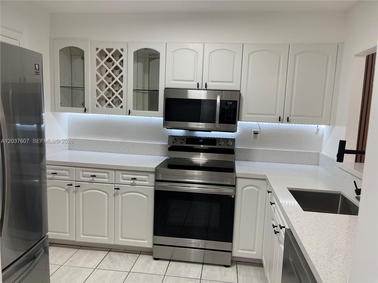 A white hallway features tiled flooring, a louvered door, and a main entry door — 8233 Harding Ave # 408, Miami Beach FL 33141, MIAMI BEACH, FL