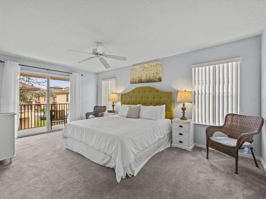 A bedroom features a tufted green headboard, white bedding, two wicker chairs, and a balcony — 408 MIRAMAR AVENUE, DAVENPORT, FL
