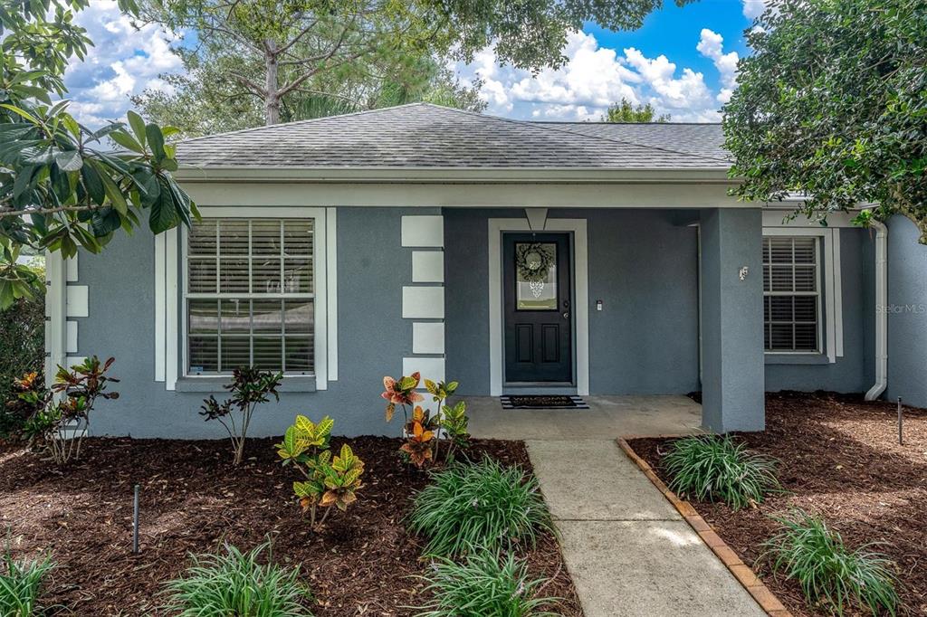 A single-story gray house with white trim, a front porch, and a landscaped front yard — 24308 LANDING DRIVE, LUTZ, FL