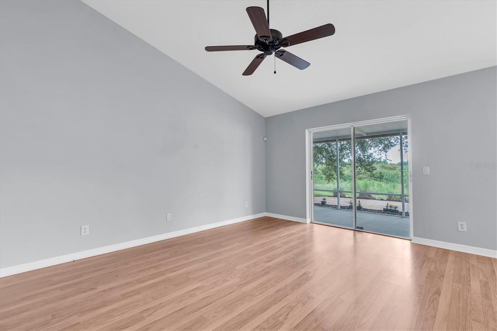An empty room with light wood flooring, gray walls, a ceiling fan, and sliding doors — 24308 LANDING DRIVE, LUTZ, FL