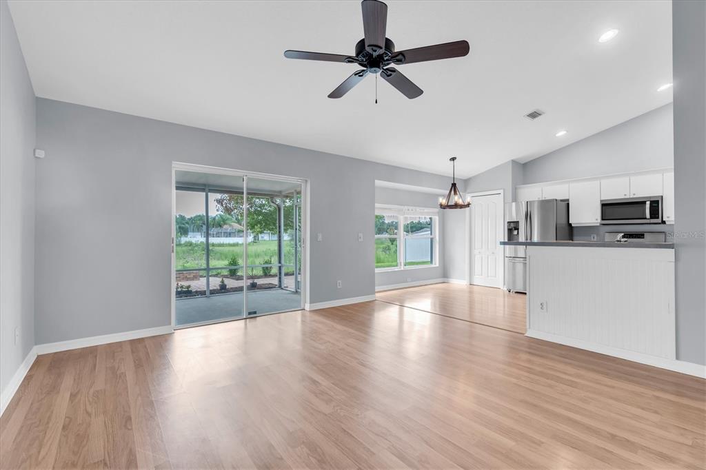 A living room with light wood floors, a ceiling fan, and a sliding glass door — 24308 LANDING DRIVE, LUTZ, FL