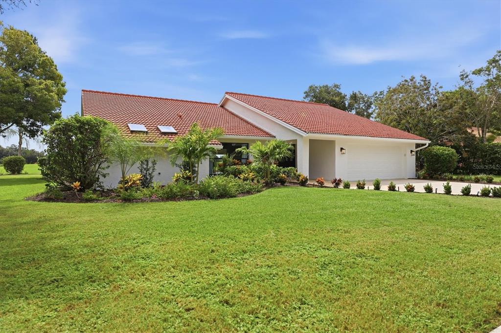 A single-story house with a red tile roof, white exterior, and a large front lawn — 8822 MISTY CREEK DRIVE, SARASOTA, FL