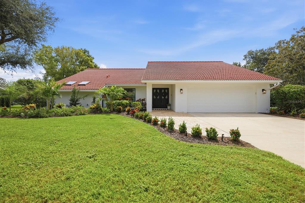 A single-story house with a red tile roof, white exterior, and a two-car garage — 8822 MISTY CREEK DRIVE, SARASOTA, FL
