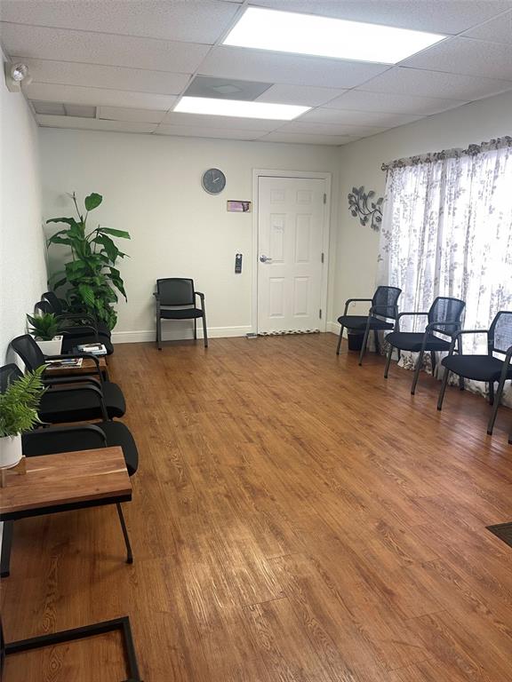 A waiting room with wood-look flooring, several black chairs, and a white door — 2609 SW 33RD STREET UNIT 101-4, OCALA, FL